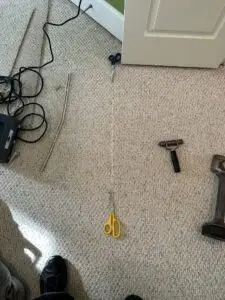 Unraveled Berber carpet loop run with repair tools lying on the floor.